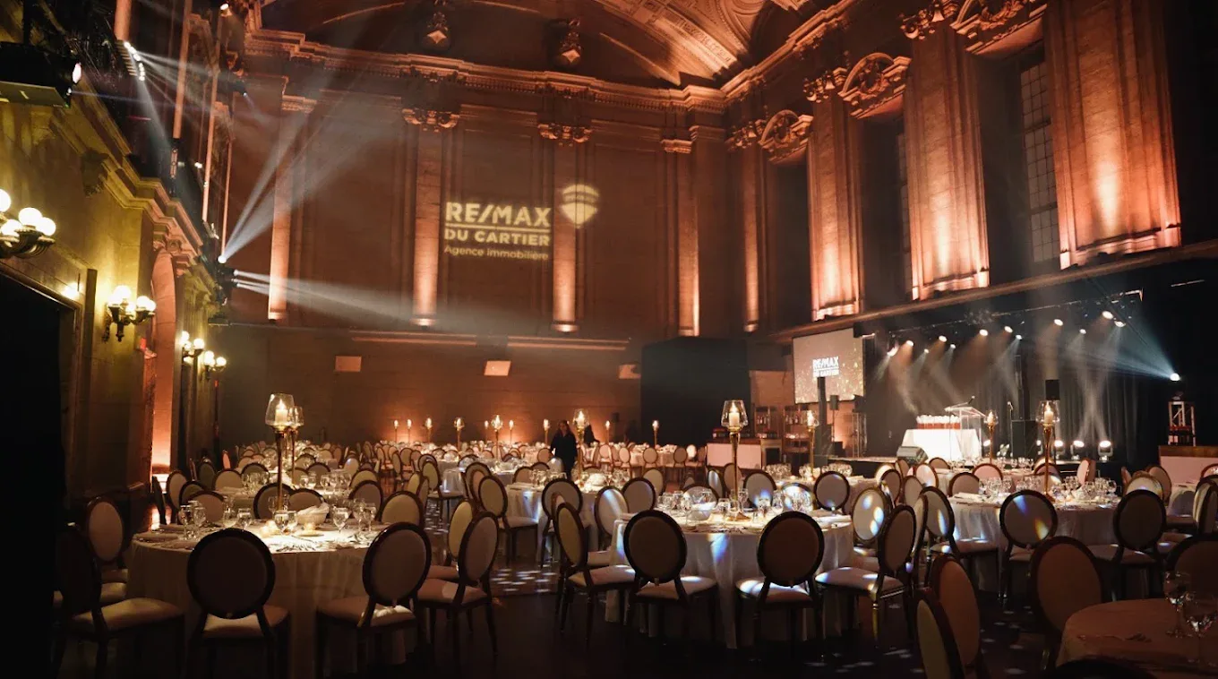 Gala RE/MAX du Cartier au Théâtre St-James, logo en gobo projeté au-dessus d'une salle à souper aux chandelles